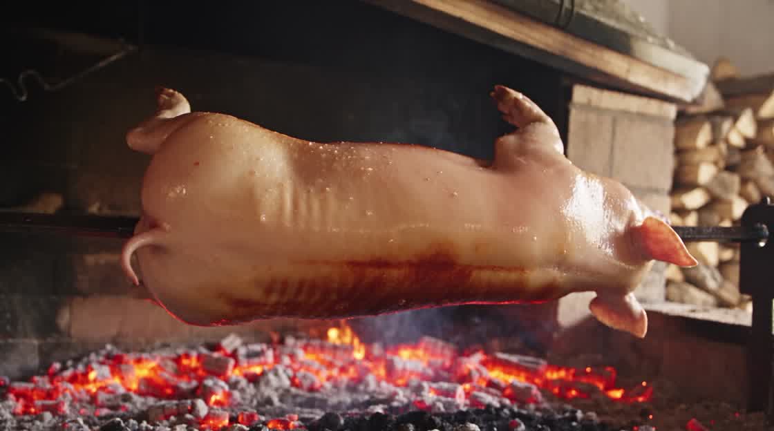 Odojak se okreće na ražnju iznad žara